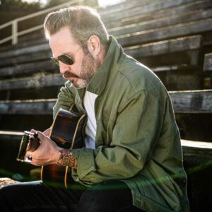 Steve Marriner posing on bleachers with guitar