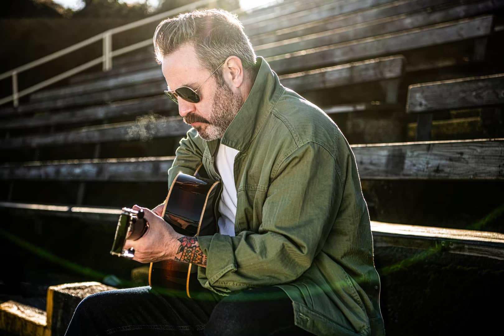 Steve Marriner posing on bleachers with guitar