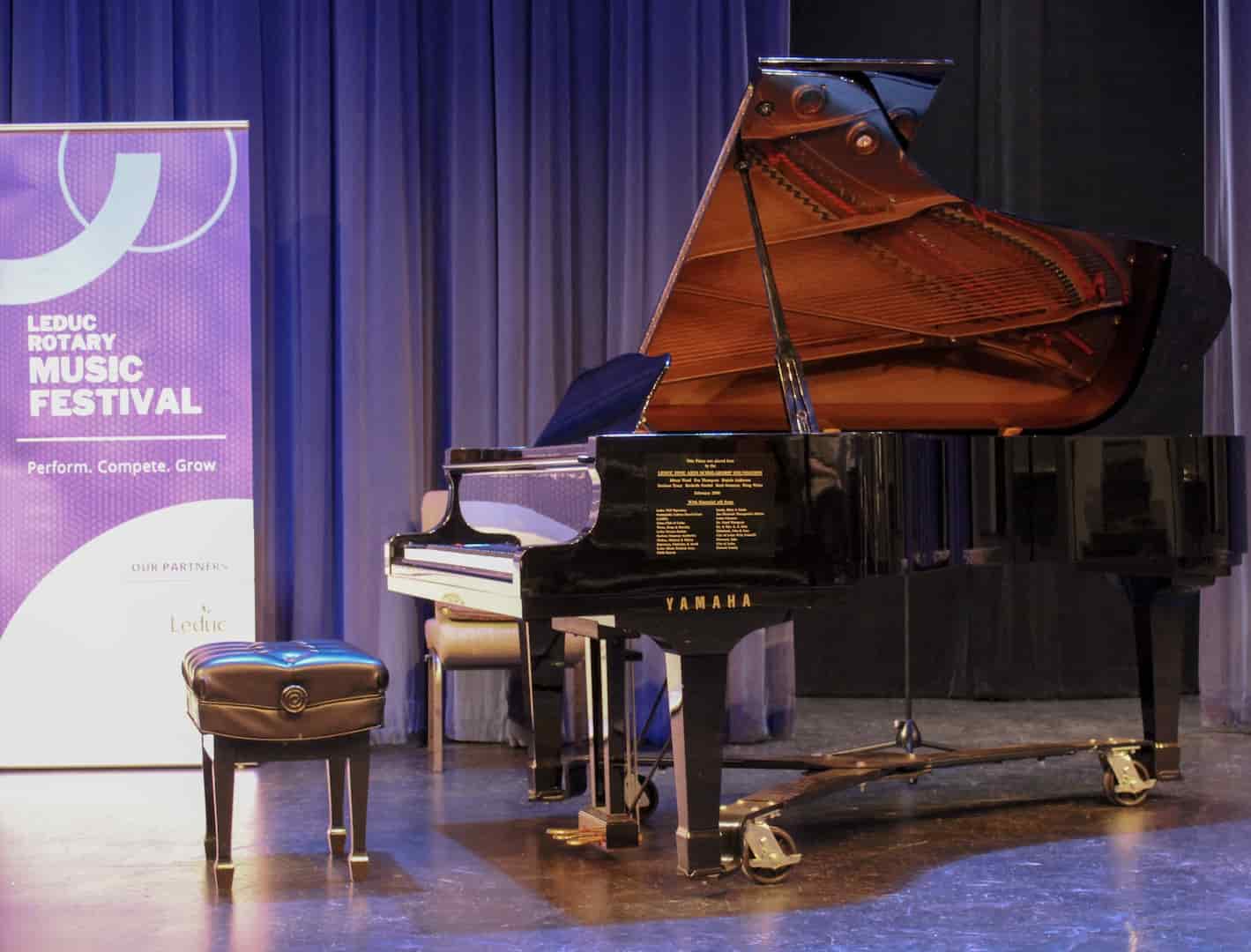 Piano on stage with Leduc Music Festival banner in the background