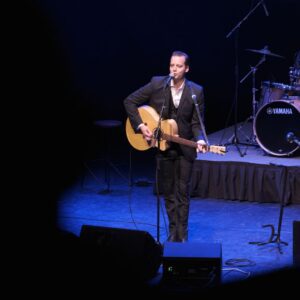 Folsom Prison Revisited promo photo on stage performing with guitar
