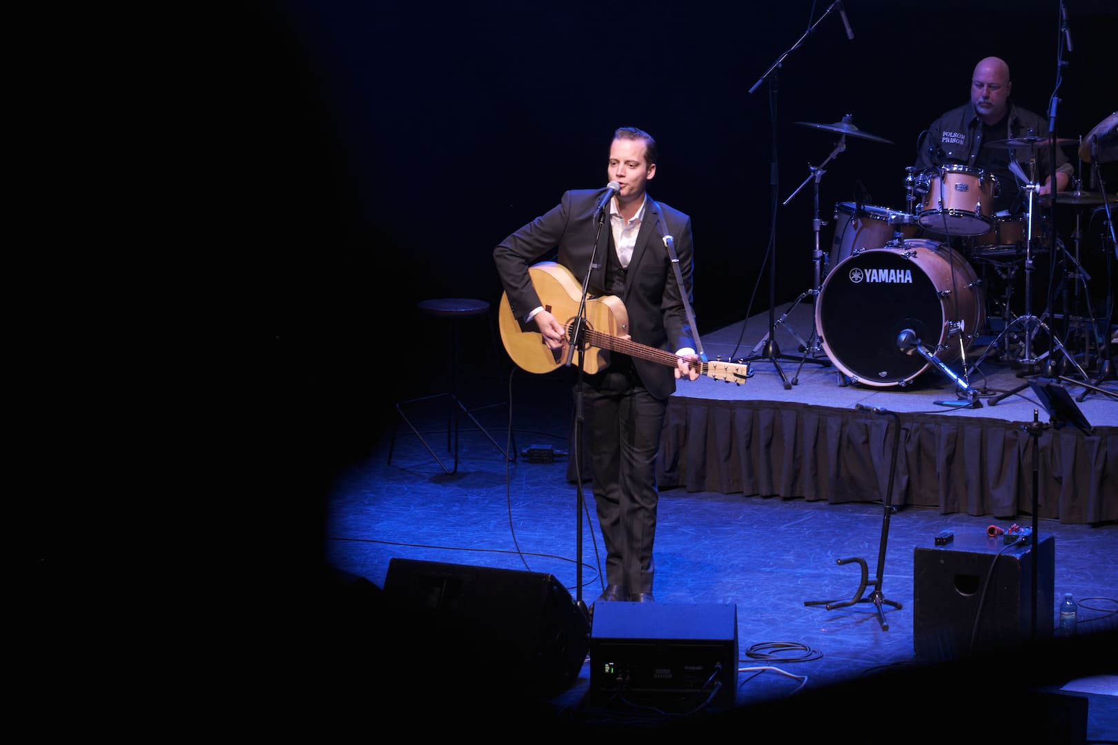 Folsom Prison Revisited promo photo on stage performing with guitar