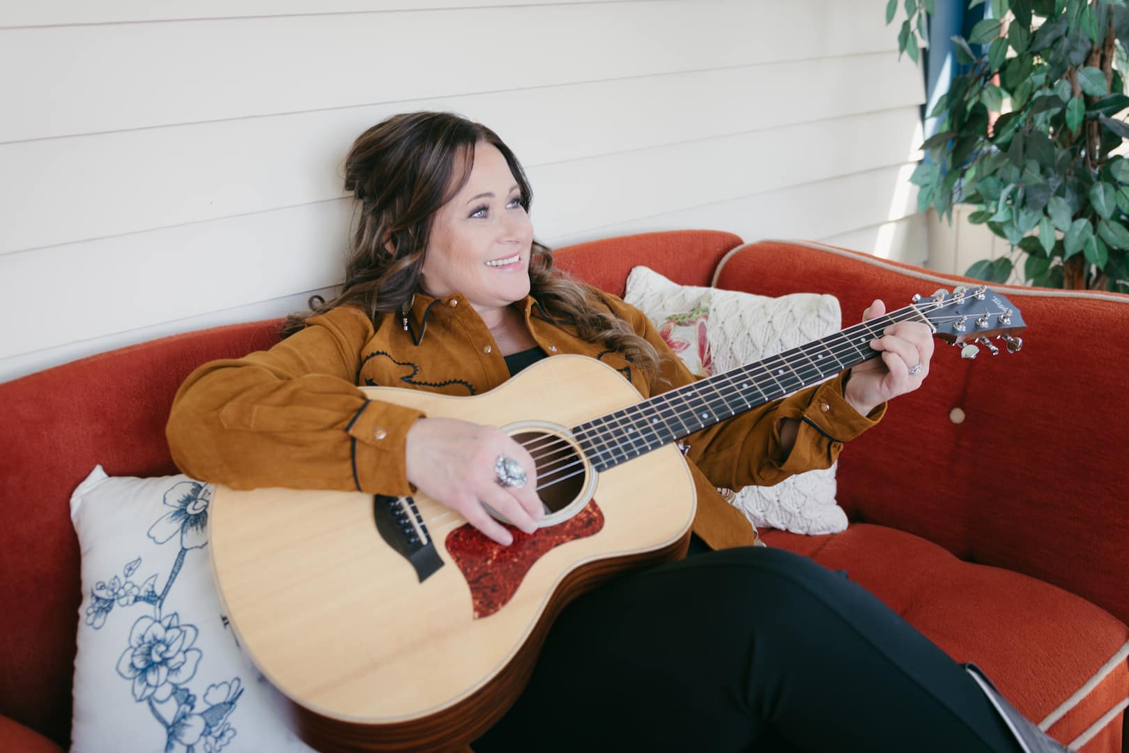 Tracy Millar photo holding guitar sitting on couch